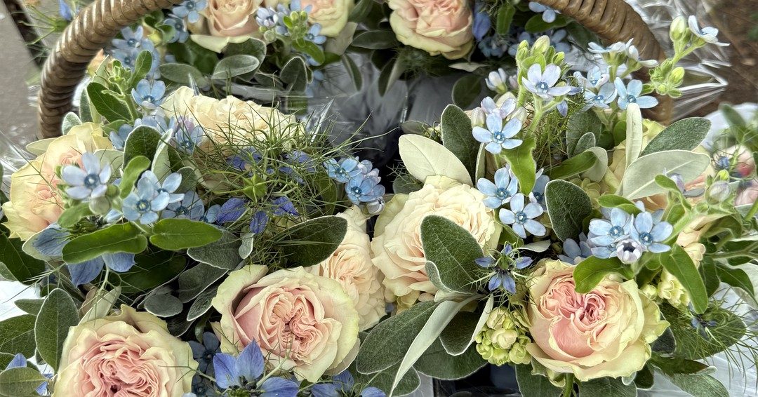 Close-up of a seasonal arrangement of cream roses and blue delphiniums